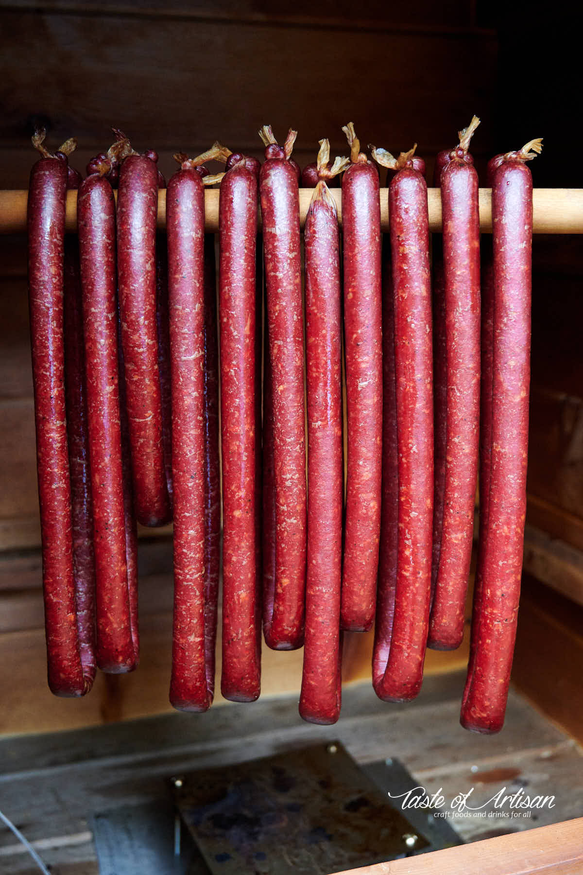 Beef stick hanging on a stick inside a smokehouse.