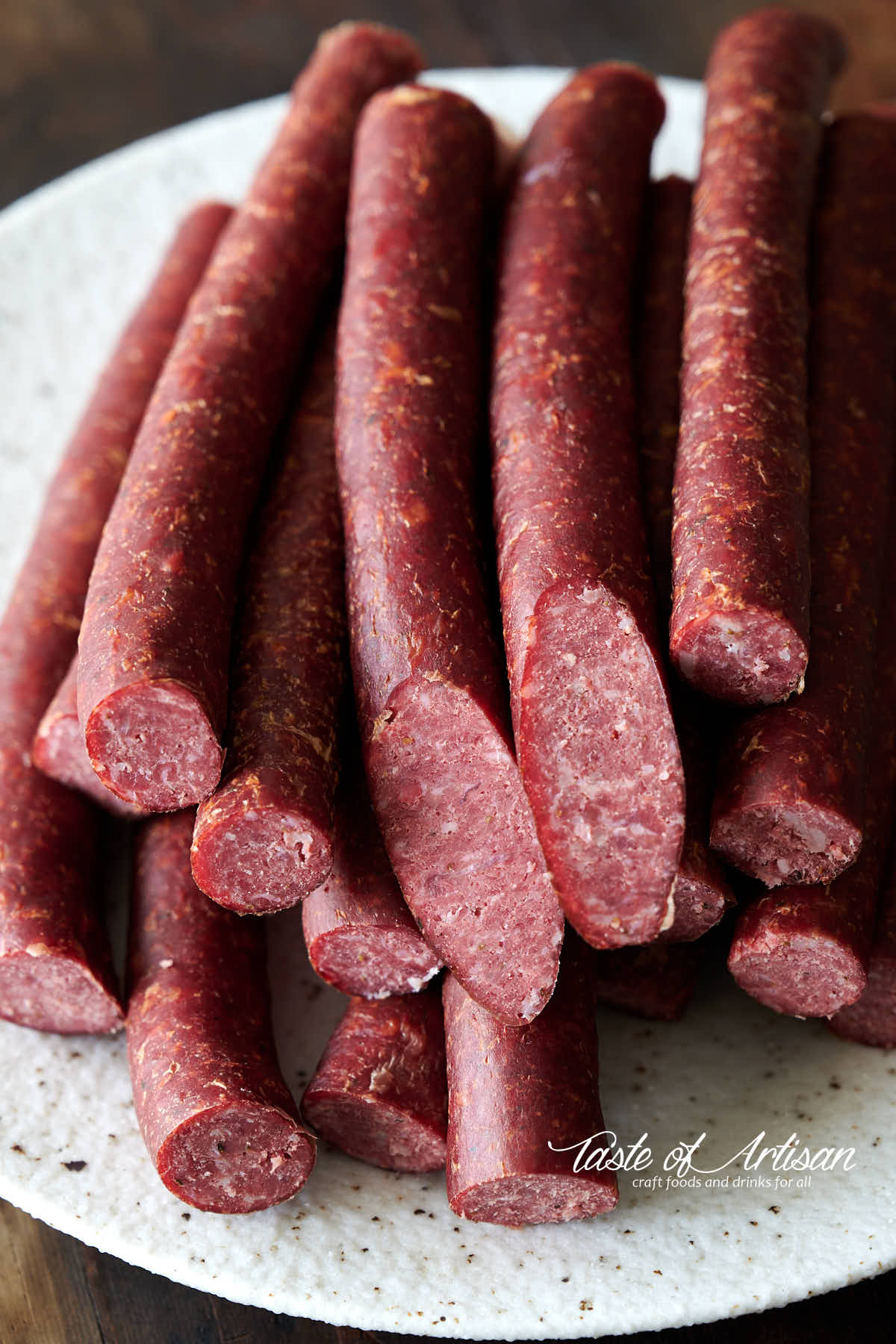 Smoked beef sticks on a speckled plate.