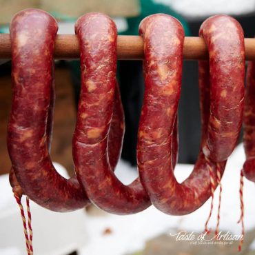 Smoked garlic sausage hanging on a stick.