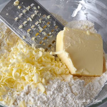 Grating butter over flour mix.