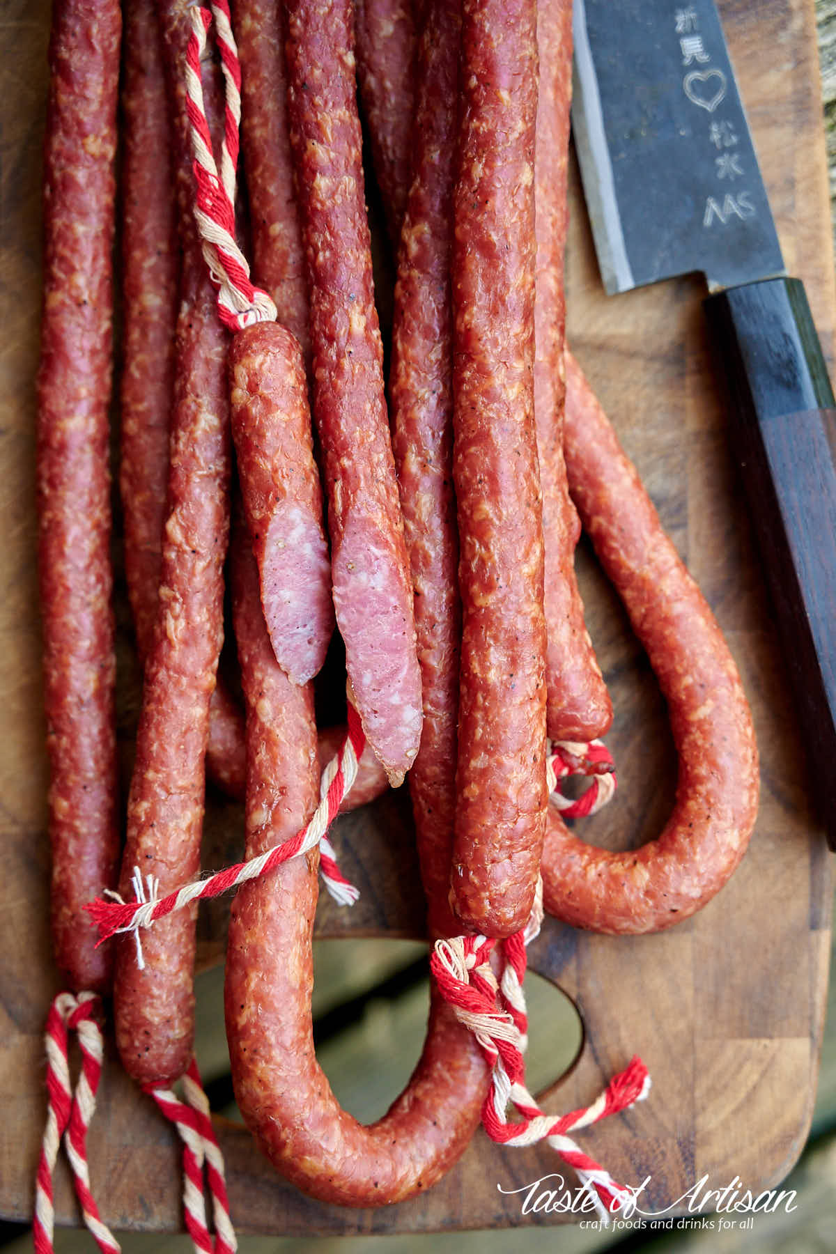 Kabanos sausage on a cutting board next to a knife.