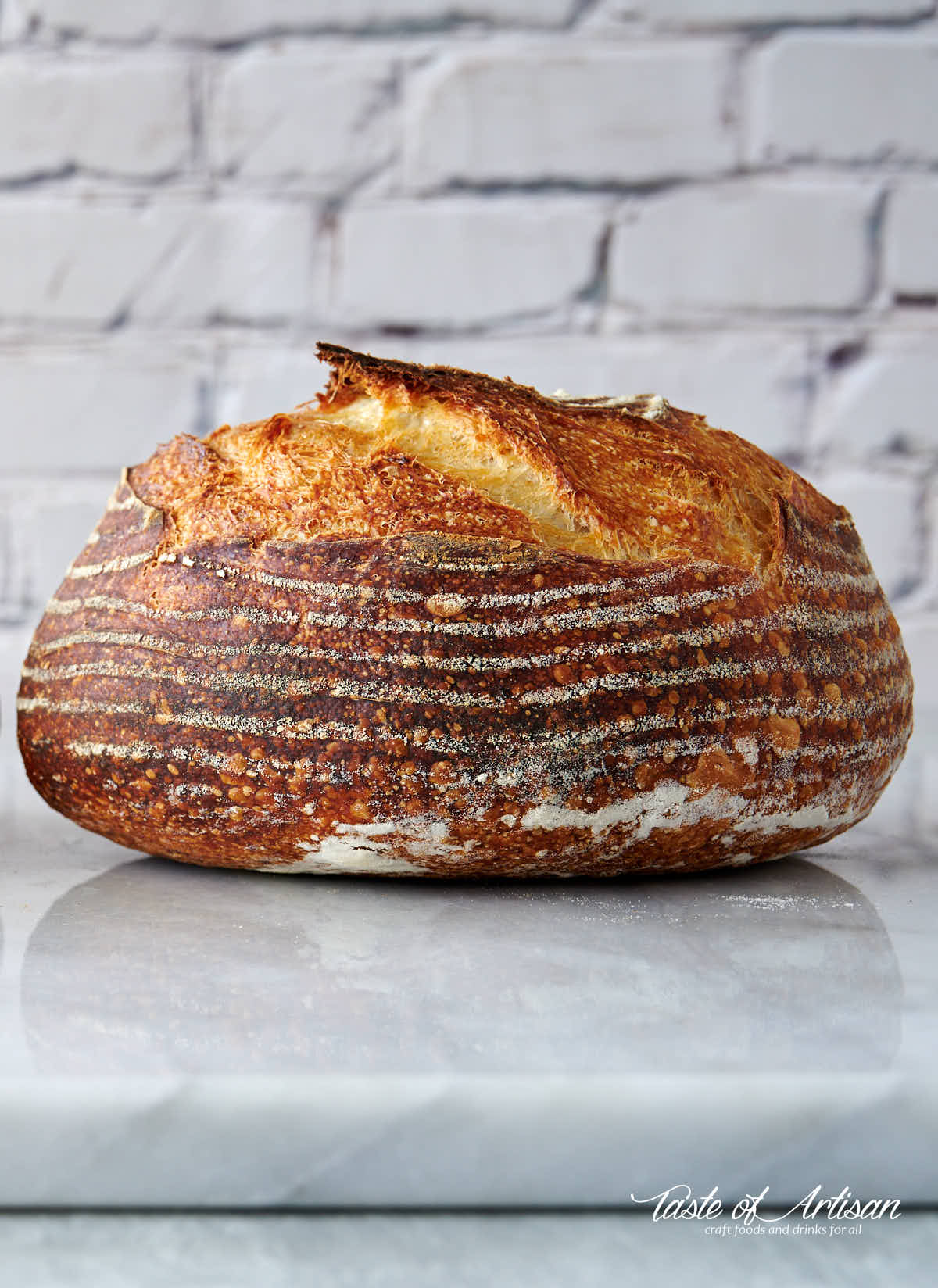 Whole no-knead sourdough bread on a marble slab.