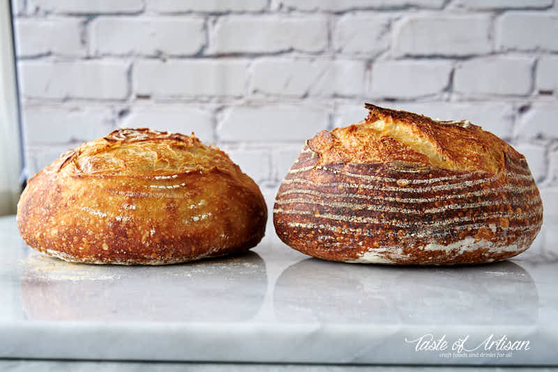 Two loaves of bread side by side on a marble table.