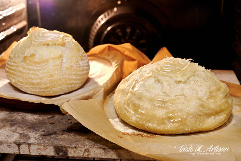 Two loaves of bread in the oven on a baking stone.