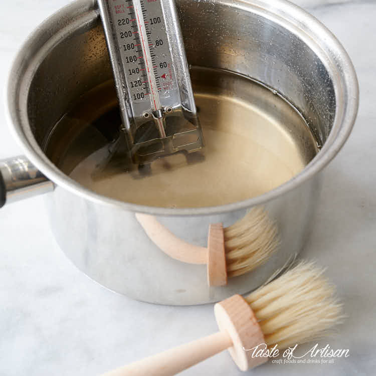 Making invert sugar in a pot, with candy thermometer and a pastry brush.