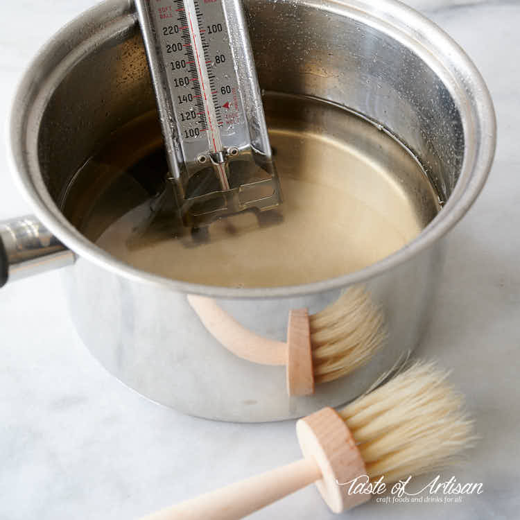 Hacer azúcar invertido en una olla, con termómetro de dulces y una brocha de pastelería.