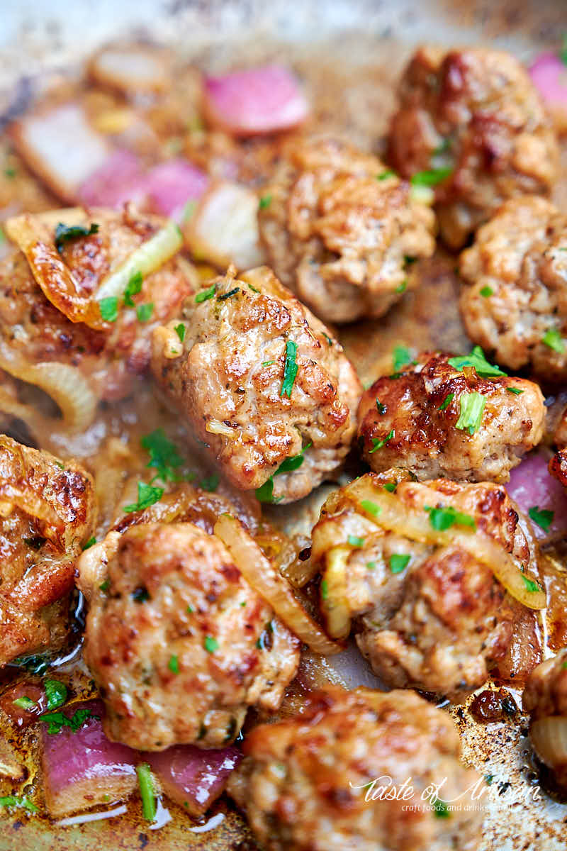 Italian sausage. shaped as meatballs, frying in a pan.