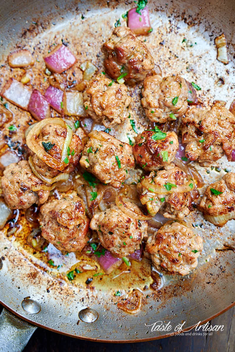 Italian sausage. shaped as meatballs, frying in a pan.