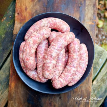 Freshly made Italian sausage links on a black plate.