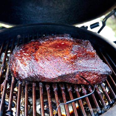 Brisket flat on the rack of a smoker.