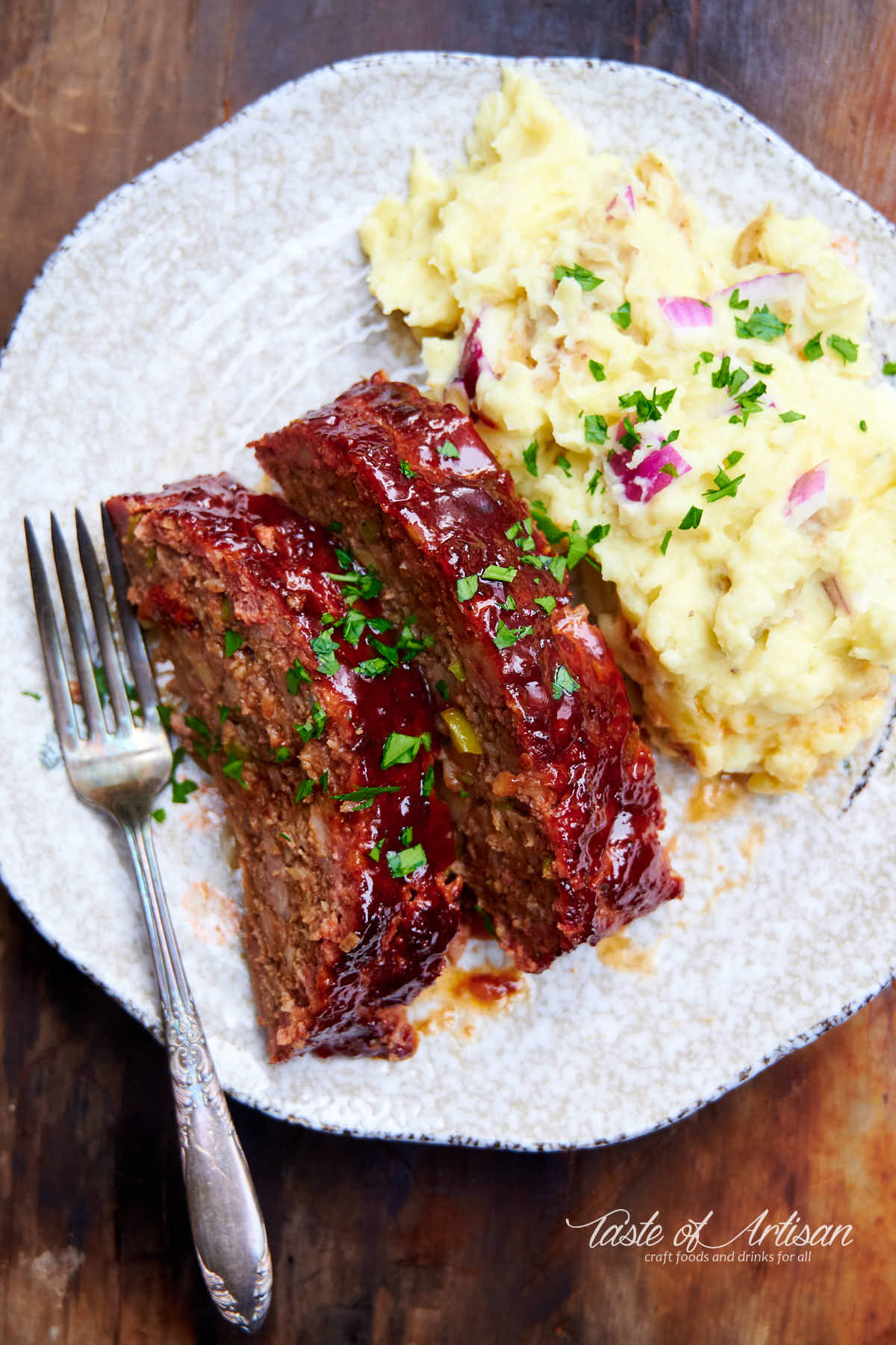 Smoked meatloaf slices on a plate with a fork and mashed potatoes.