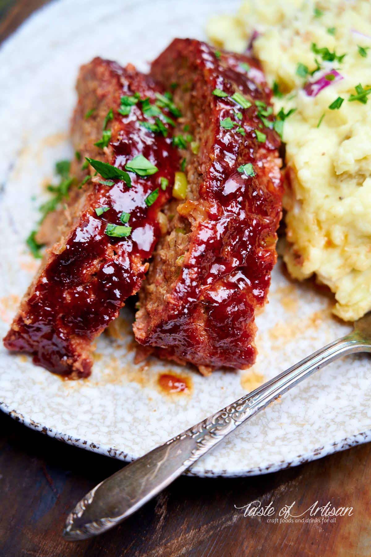 Smoked meatloaf slices on a plate with a fork and mashed potatoes.