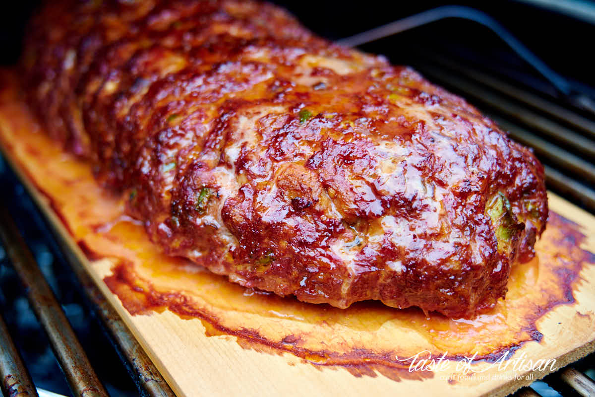 Meatloaf smoking on a cedar plank inside a smoker.