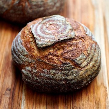 A loaf or rustic sourdough bread on a cutting board.