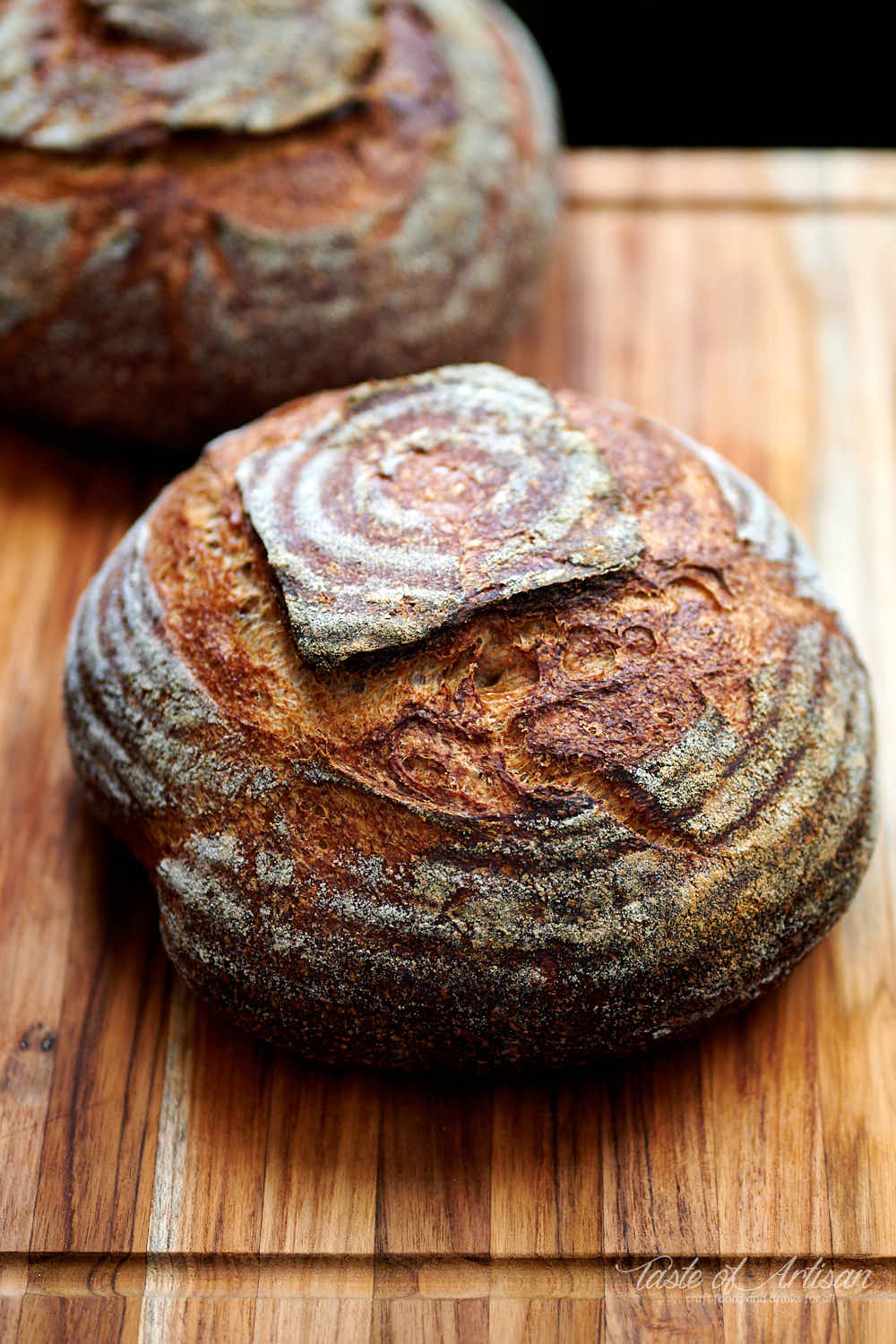 Two sourdough whole what bread loaves on a wooden board.