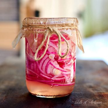 Sliced red onion in a jar with pickling juice.