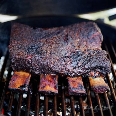 Beef short ribs smoking in a smoker.