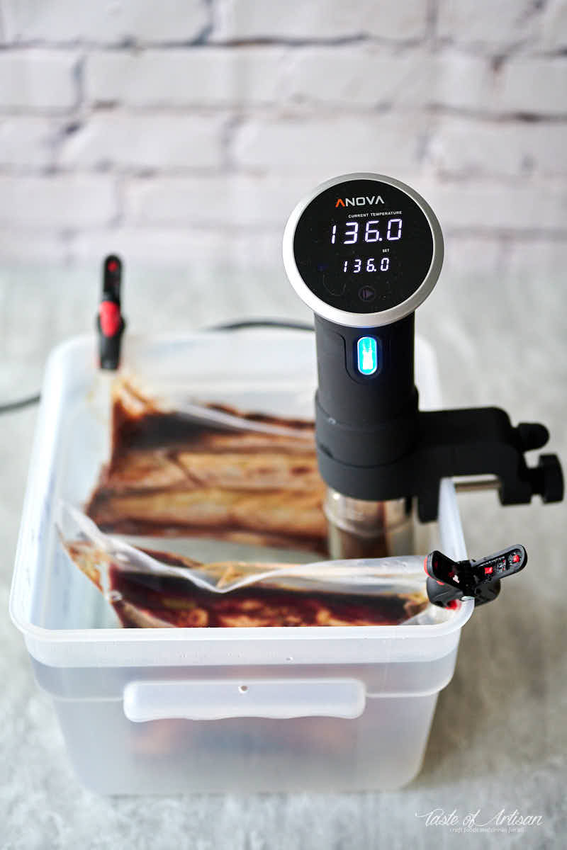 Beef short ribs inside a sous vide bath with sous vide circulator.