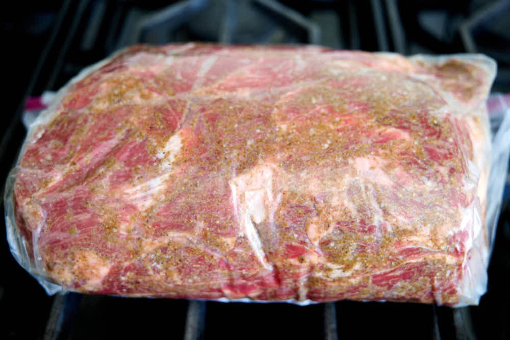 Seasoned beef chuck roast in a Ziploc bag.