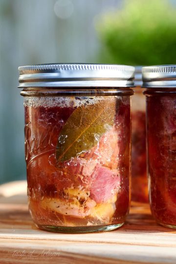 Canned beef in a glass jar with golden juice.