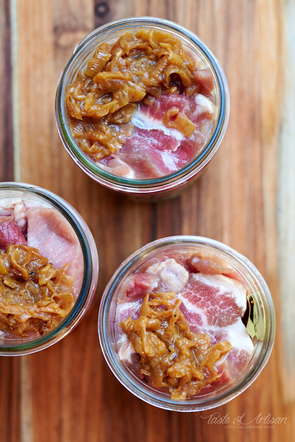 Stuffing pork and onions in mason jars.