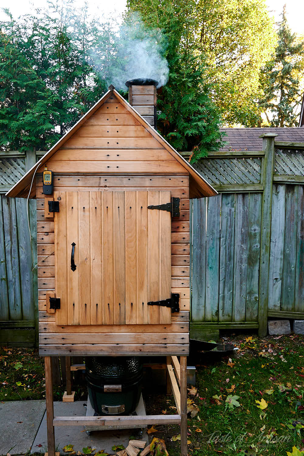 Wooden smokehouse with smoke coming out of chimney.