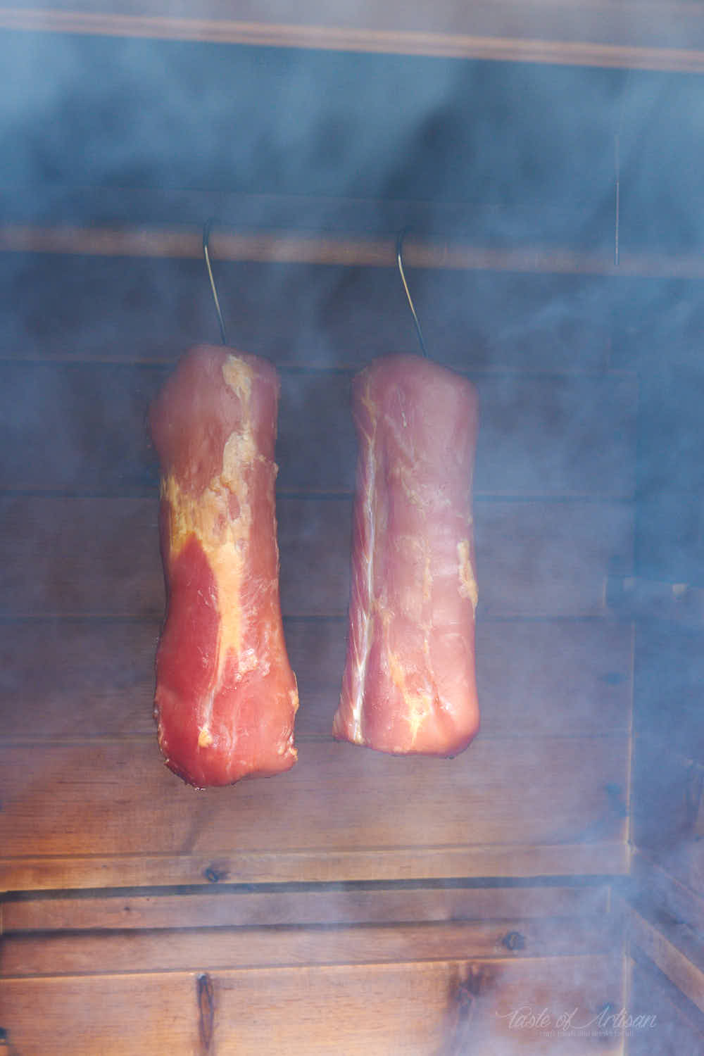 Pork loins hanging in a smokehouse.