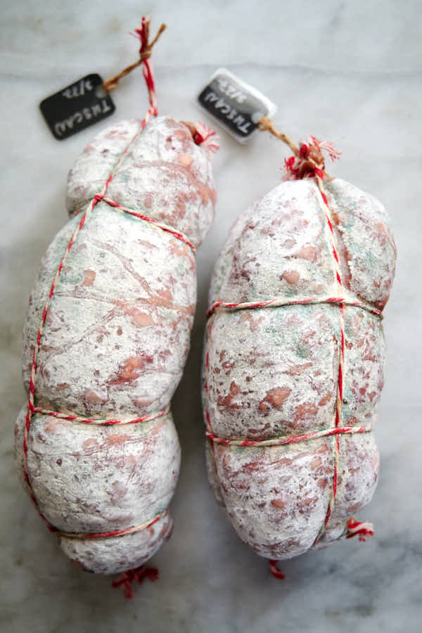 Salami with white and good green mold on a marble slab.