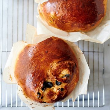 Top down view of two panettone loaves on a cooling rack.