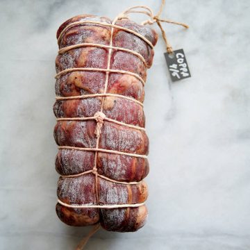Whole dry cured capicola on a table.