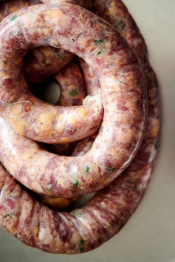 A long freshly made jalapeno cheddar sausage coiled on a table.