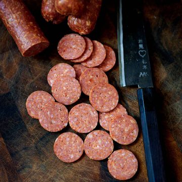 Sliced pepperoni on a cutting board.