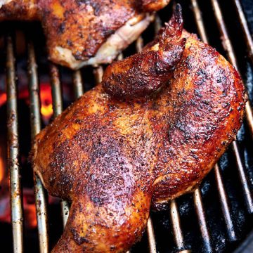 Chicken halves on a smoker grate.