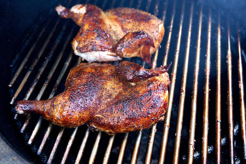 Smoking chicken halves over direct heat skin side up.