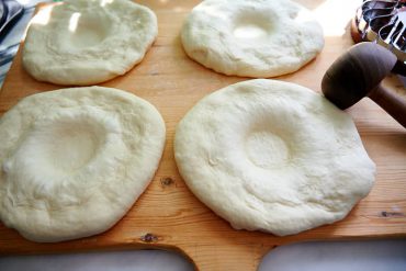 Pressing down center of dough for Uzbek bread obi non.