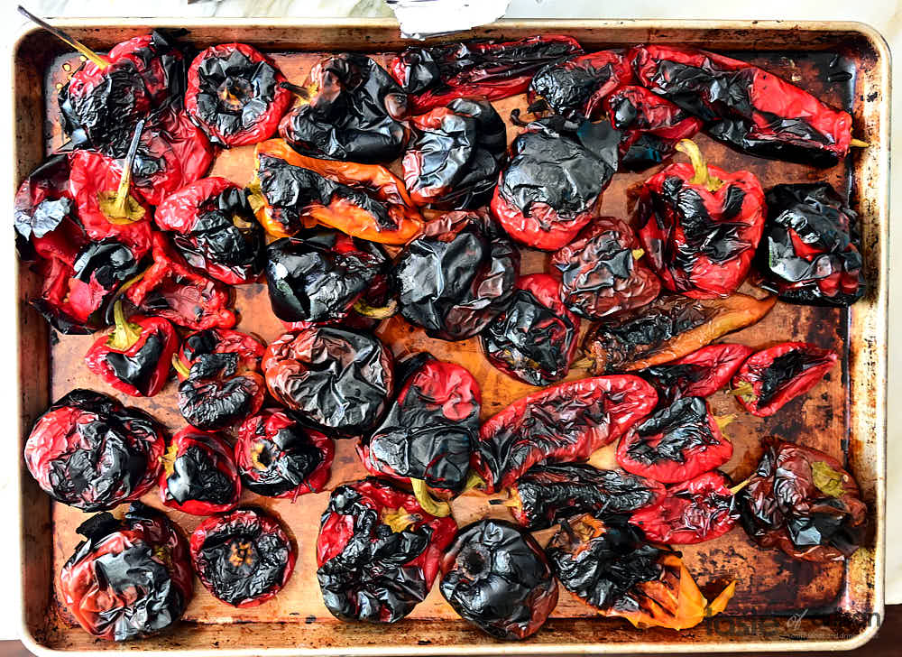 Fully charred and blistered peppers on a baking sheet
