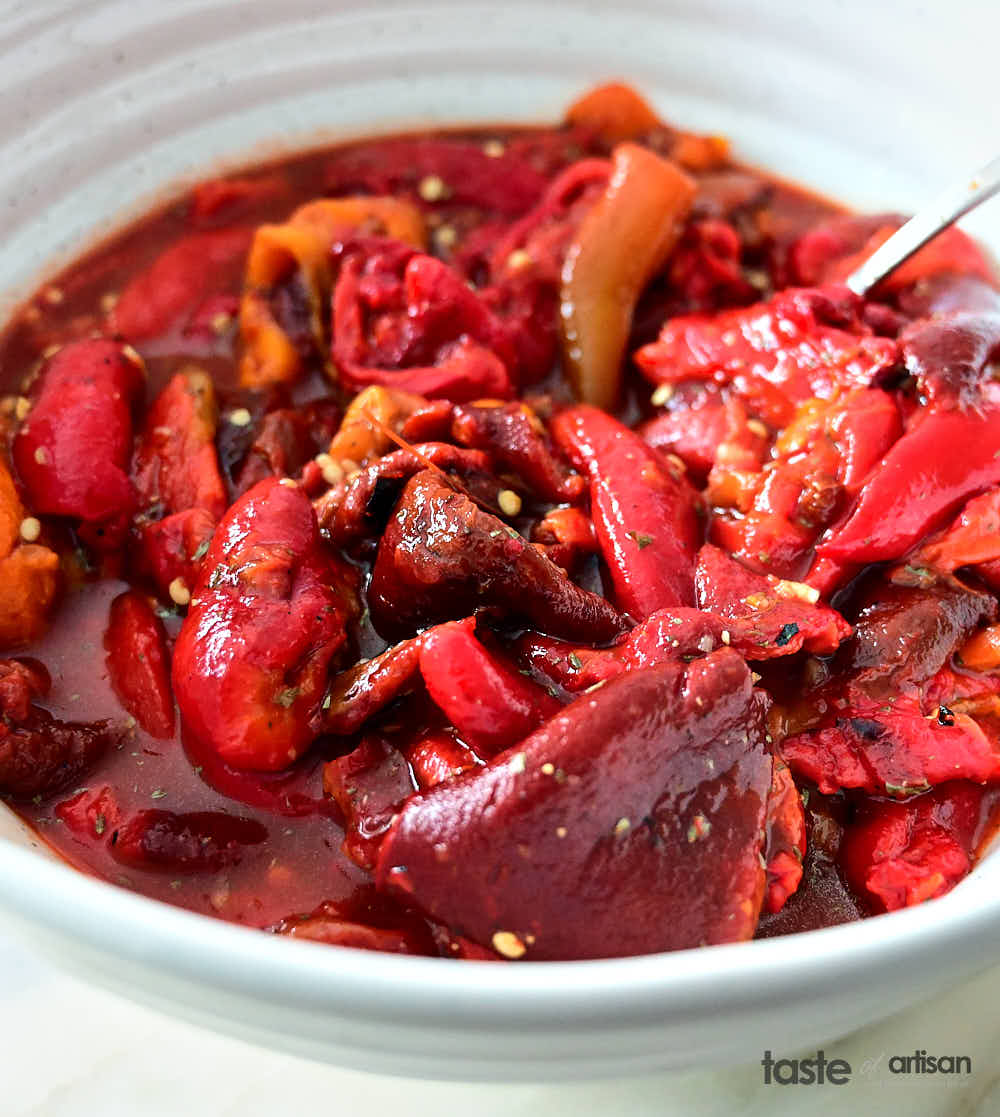 Peeled roasted peppers with seasonings in bowl before canning.