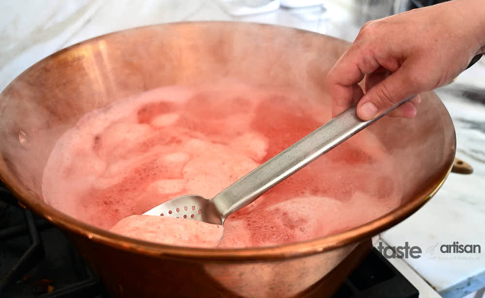 Skimming foam off boiling strawberry jam.