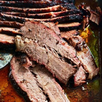 Slices of juicy smoked brisket in a pan.