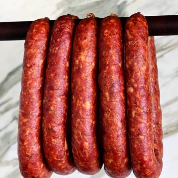Traditional homemade Hungarian sausage hanging on a smoker dowel.