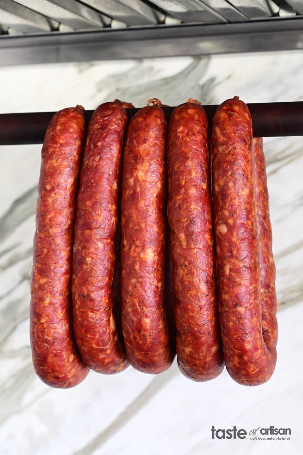 Traditional homemade Hungarian sausage hanging on a smoker dowel.