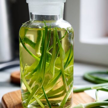 A bottle with oil and garlic scapes inside.