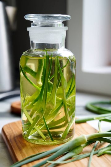 A bottle with oil and garlic scapes inside.