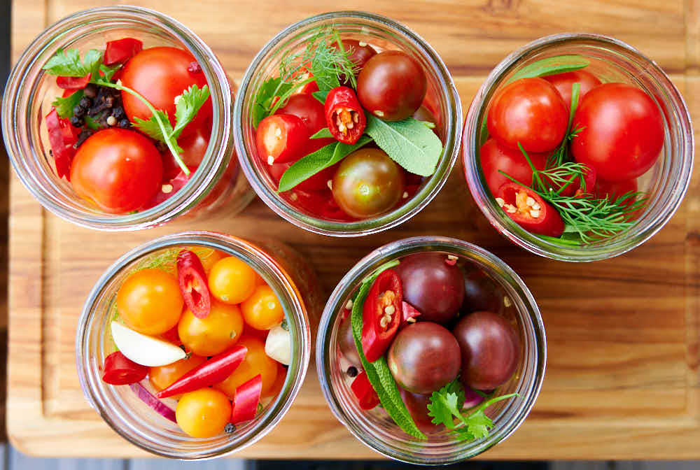 Jars filled with cherry tomatoes and seasonings.
