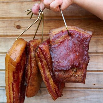 Smoked bacon pieces hanging on steel hooks