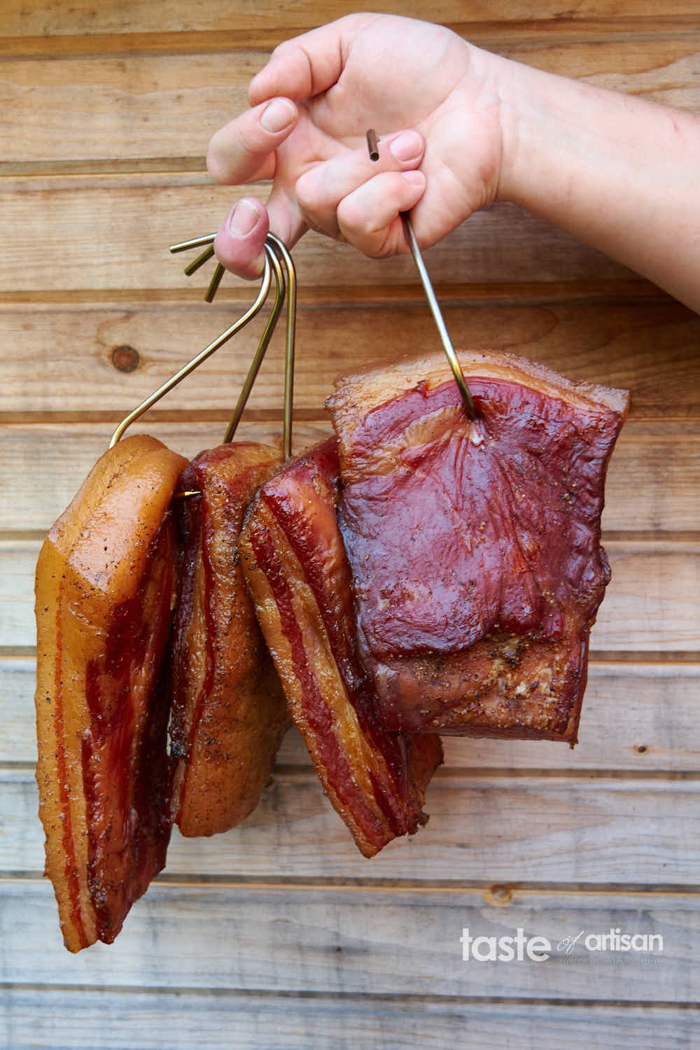 Smoked bacon pieces hanging on steel hooks