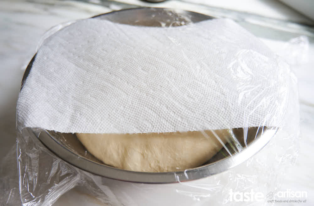Pizza dough covered with plastic.