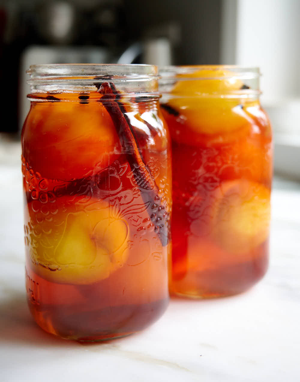 Pickled peaches in jars filled with pickling brine.