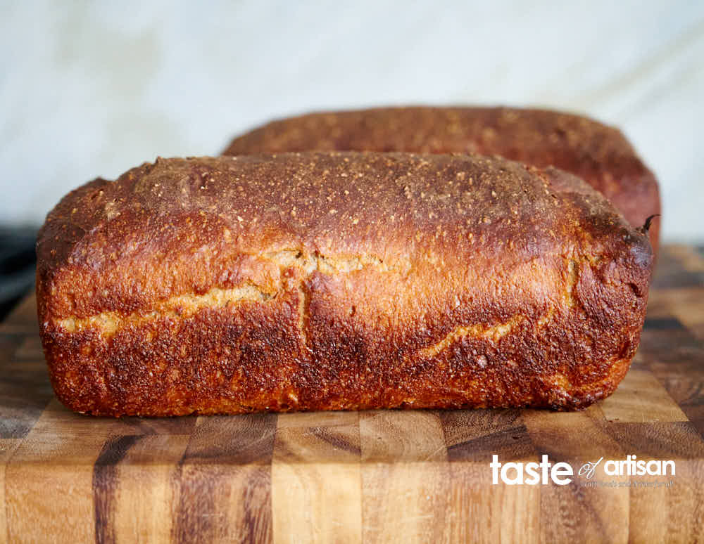 Gorgeous golden brown loaf of dark rye bread.