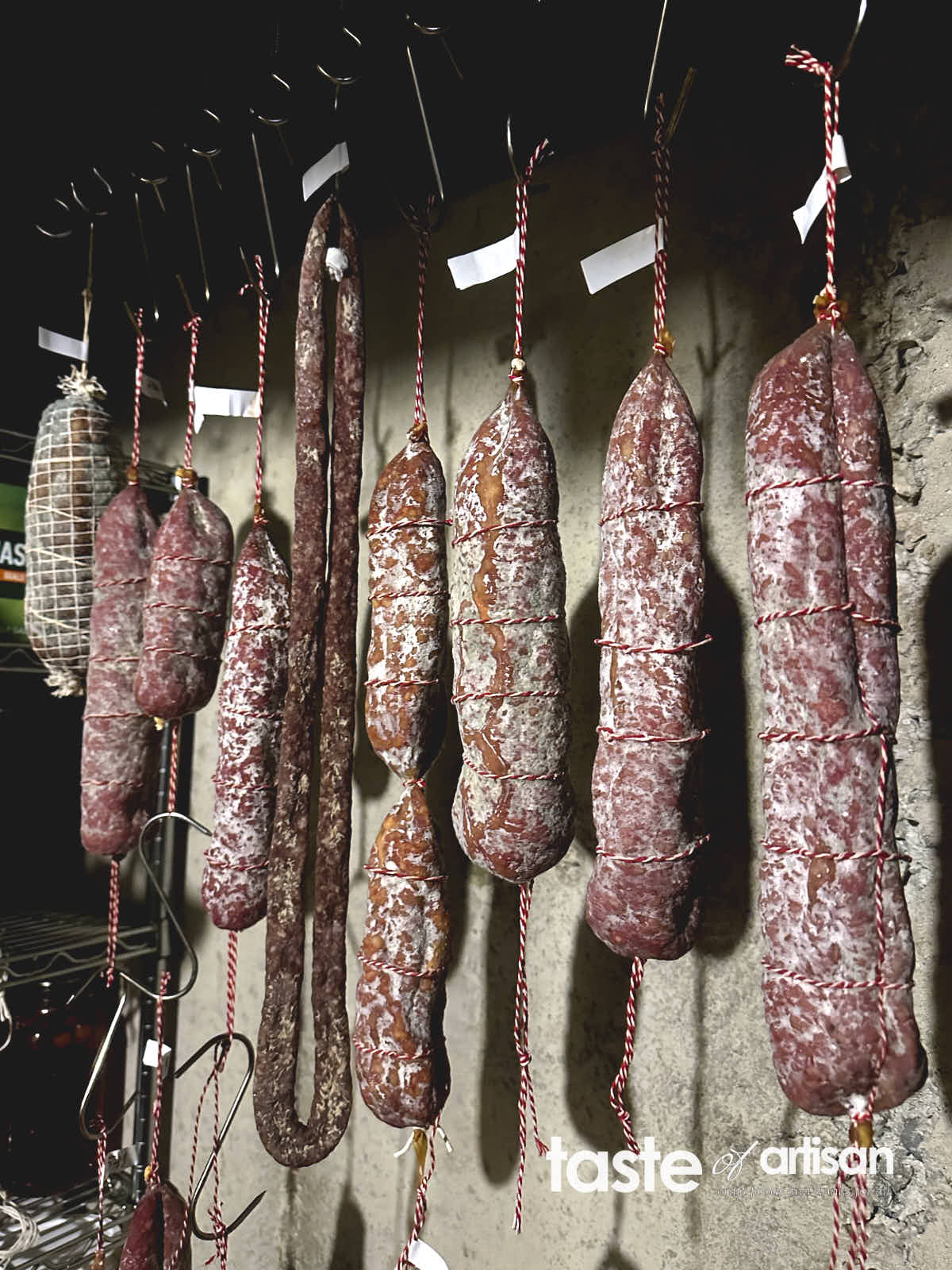 Salami and capicala hanging in a meat curing cellar.